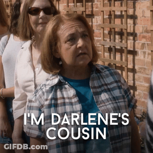 A Woman In A Plaid Shirt Says " I 'M Darlene 'S Cousin " In Front Of A Group Of People GIF