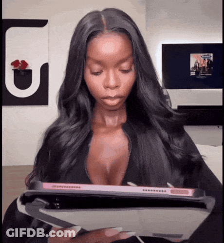 A Woman In A Plunging Top Is Holding A Tablet GIF