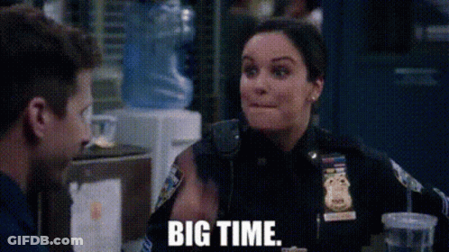 A Woman In A Police Uniform Is Sitting At A Table With A Man And Talking To Him . GIF