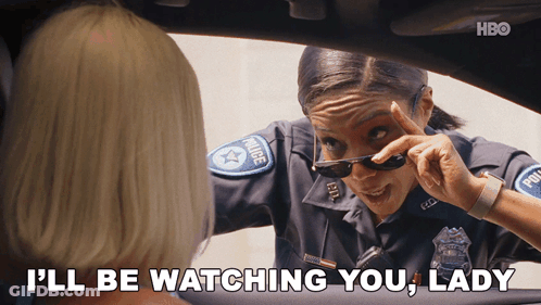 A Woman In A Police Uniform Says " I 'Ll Be Watching You Lady " While Wearing Sunglasses GIF