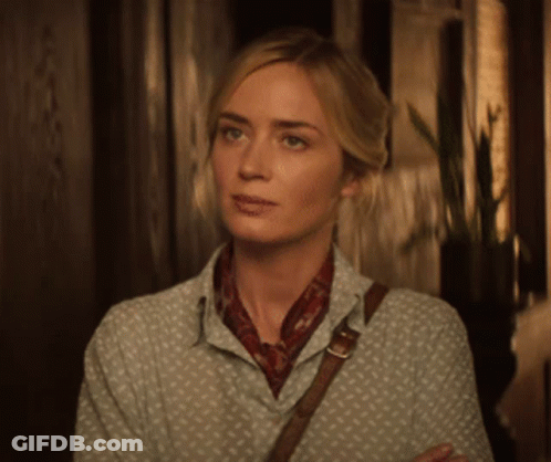 A Woman In A Polka Dot Shirt And Scarf Is Standing In A Hallway GIF