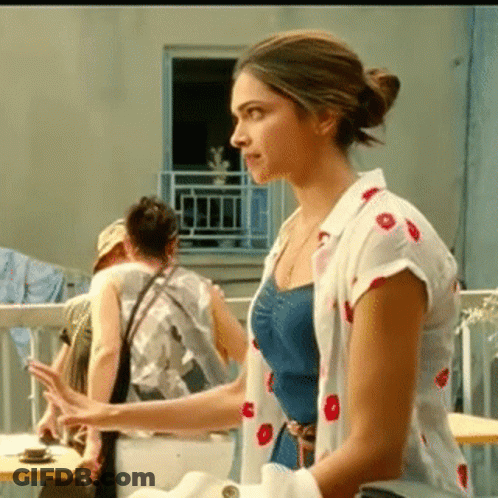 A Woman In A Polka Dot Shirt Is Standing On A Balcony . GIF