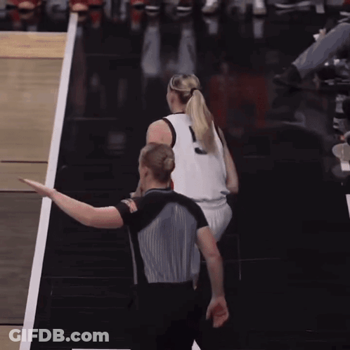 A Woman In A Ponytail Stands Next To A Referee GIF
