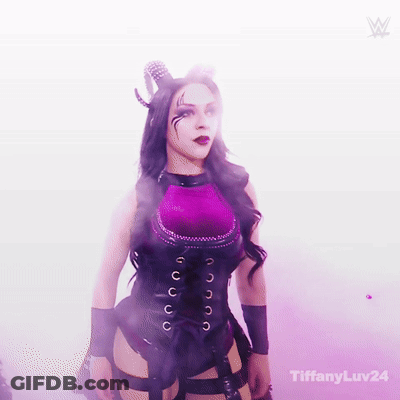 A Woman In A Purple And Black Costume With Horns Is Standing In A Room With Smoke Coming Out Of It . GIF