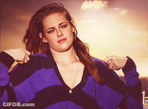 A Woman In A Purple And Black Striped Sweater Is Adjusting Her Sweater GIF