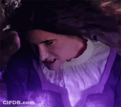 A Woman In A Purple Dress And A White Collar Is Standing In Front Of A Purple Light . GIF
