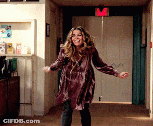 A Woman In A Purple Dress Is Dancing In A Hallway With A Red Exit Sign Above Her GIF