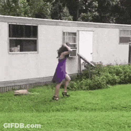 A Woman In A Purple Dress Is Dancing In Front Of A White Trailer . GIF