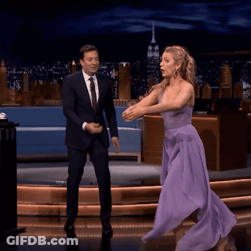 A Woman In A Purple Dress Is Dancing On A Stage With A Man In A Suit GIF