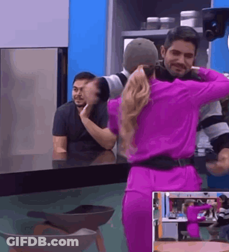 A Woman In A Purple Dress Is Dancing With A Man In A Kitchen . GIF