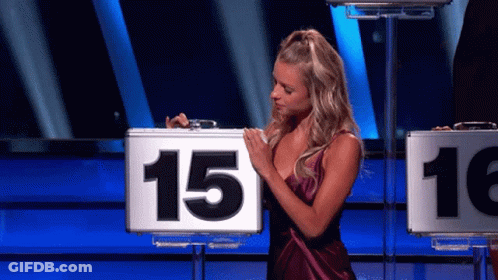 A Woman In A Purple Dress Is Holding A Briefcase With The Number 15 On It GIF