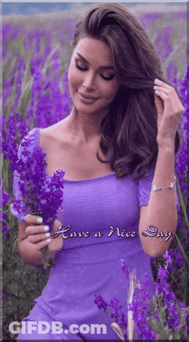 A Woman In A Purple Dress Is In A Field Of Purple Flowers With The Words Have A Nice Day Below Her GIF