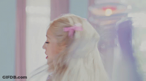 A Woman In A Purple Dress Is Looking At Her Reflection In A Mirror GIF