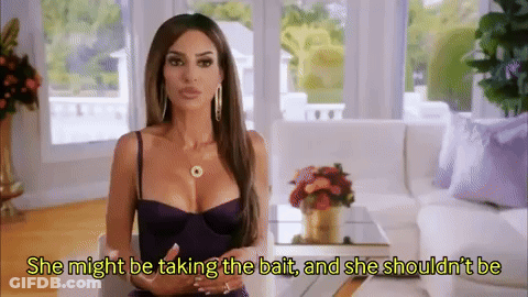 A Woman In A Purple Dress Is Sitting In A Living Room With A Couch . GIF