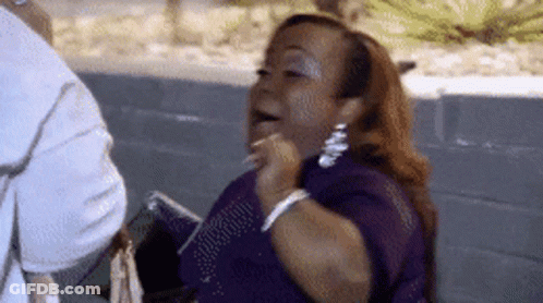 A Woman In A Purple Dress Is Sitting Next To A Man And Holding A Cell Phone . GIF