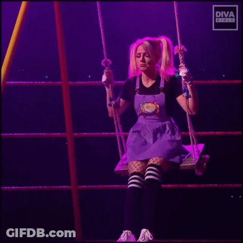 A Woman In A Purple Dress Is Sitting On A Swing In A Ring . GIF