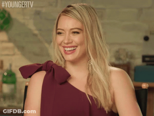 A Woman In A Purple Dress Is Smiling And Sitting In A Chair With #Youngertv Written Above Her GIF