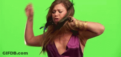 A Woman In A Purple Dress Is Standing In Front Of A Green Screen And Holding Her Hair . GIF