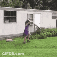 A Woman In A Purple Dress Is Standing In Front Of A White Trailer . GIF