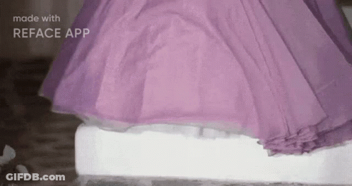 A Woman In A Purple Dress Is Standing On A White Block Of Ice . GIF