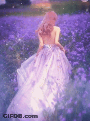 A Woman In A Purple Dress Walking Through A Field Of Purple Flowers GIF