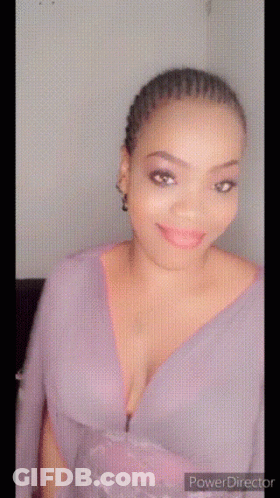 A Woman In A Purple Dress With A Plunging Neckline Is Smiling GIF