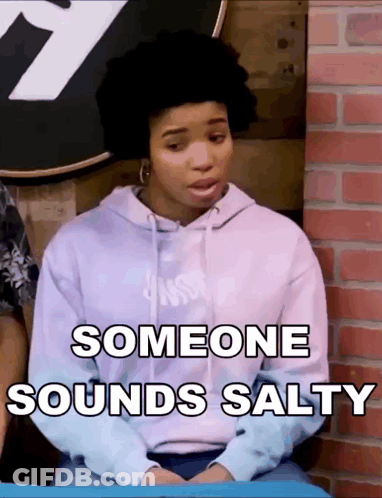 A Woman In A Purple Hoodie Is Sitting In Front Of A Brick Wall And Someone Sounds Salty GIF