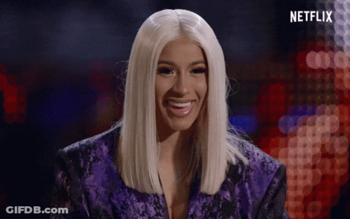 A Woman In A Purple Jacket Is Smiling In Front Of A Sign That Says Netflix GIF