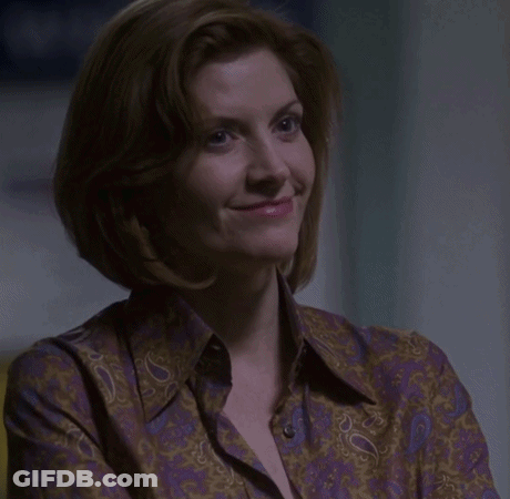 A Woman In A Purple Paisley Shirt Is Smiling GIF