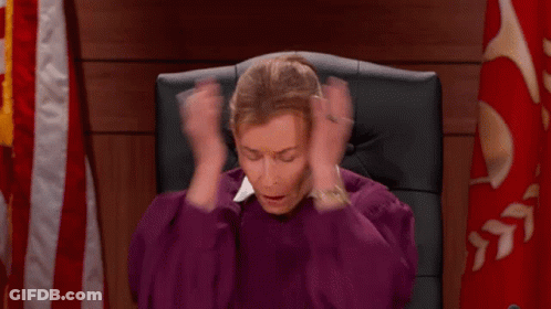 A Woman In A Purple Robe Is Sitting In A Chair Holding Her Hands To Her Head . GIF