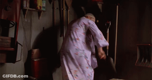 A Woman In A Purple Robe Is Standing In A Room With A Shovel GIF