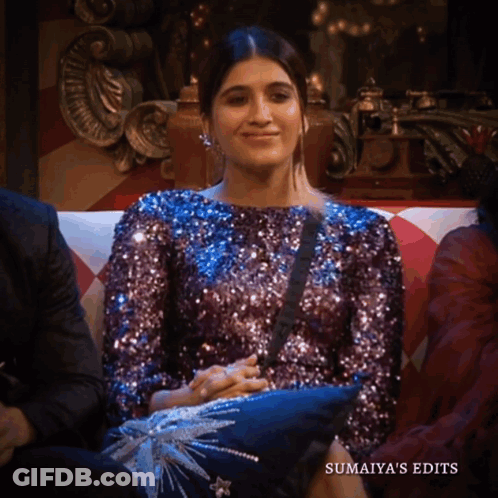 A Woman In A Purple Sequined Top Sits On A Couch With The Words Sumaiya 'S Edits Below Her GIF