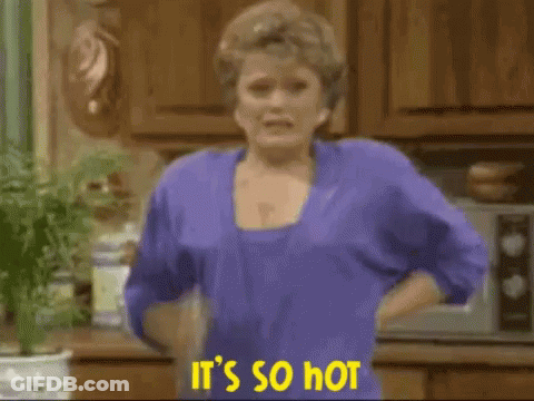 A Woman In A Purple Shirt Is Holding A Spray Bottle And Says It 'S So Hot . GIF