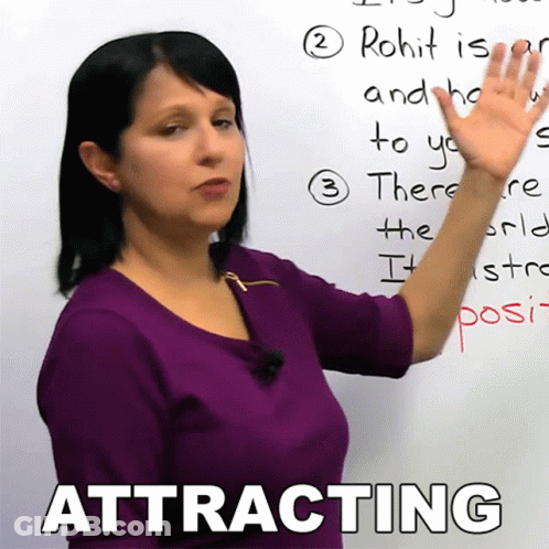 A Woman In A Purple Shirt Is Pointing At A Whiteboard With The Word Attracting On It GIF