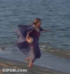A Woman In A Purple Shirt Is Running Into The Ocean GIF