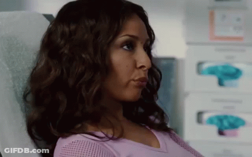 A Woman In A Purple Shirt Is Sitting In A Hospital Bed . GIF