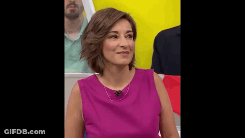 A Woman In A Purple Shirt Is Sitting In Front Of A Yellow Wall . GIF