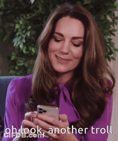 A Woman In A Purple Shirt Is Smiling While Looking At Her Phone GIF