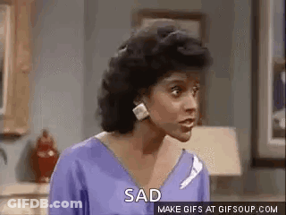 A Woman In A Purple Shirt Is Standing In A Living Room And Saying `` Sad '' . GIF