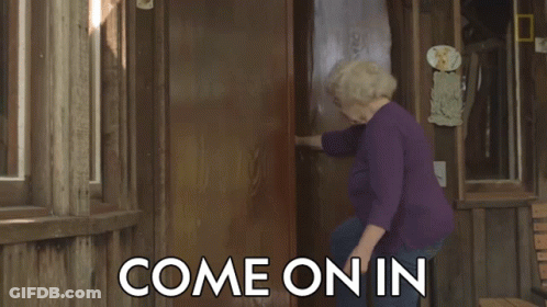 A Woman In A Purple Shirt Is Standing In Front Of A Door That Says Come On In On It GIF