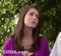 A Woman In A Purple Shirt Is Standing In Front Of A Tree And Looking Up . GIF