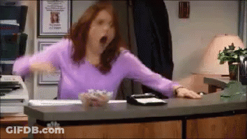 A Woman In A Purple Shirt Is Yawning At A Desk In An Office GIF