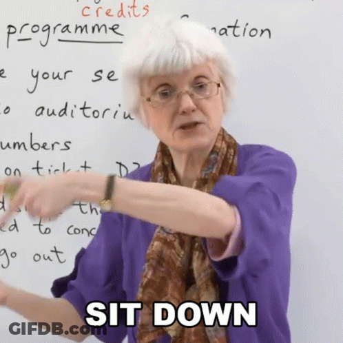 A Woman In A Purple Shirt Says Sit Down In Front Of A Whiteboard GIF
