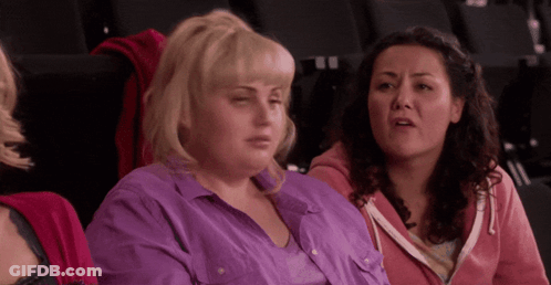 A Woman In A Purple Shirt Sits Next To Another Woman In A Pink Hoodie GIF