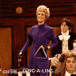 A Woman In A Purple Suit Is Holding A Triangle In Front Of A Crowd . GIF