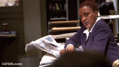 A Woman In A Purple Suit Is Reading A Newspaper . GIF