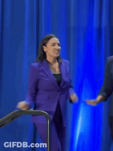 A Woman In A Purple Suit Is Smiling And Dancing GIF