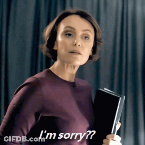 A Woman In A Purple Sweater Is Holding A Book And Says I 'M Sorry GIF