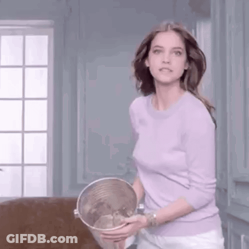 A Woman In A Purple Sweater Is Holding A Bucket Of Water In Her Hands . GIF