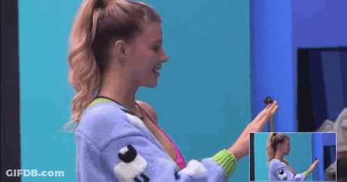 A Woman In A Purple Sweater Is Holding A Small Toy In Her Hand . GIF